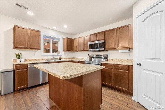 kitchen with visible vents, dark wood-style flooring, a sink, stainless steel appliances, and light countertops