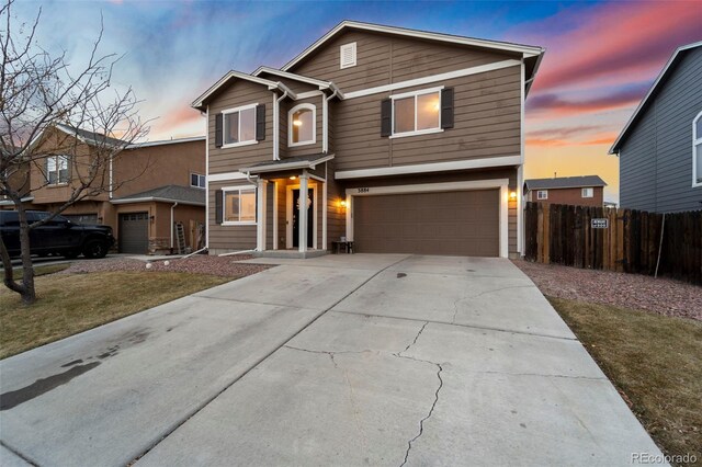 traditional-style house with an attached garage, concrete driveway, and fence