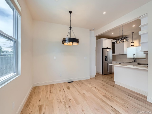 kitchen with high end fridge, healthy amount of natural light, light wood-type flooring, light countertops, and recessed lighting