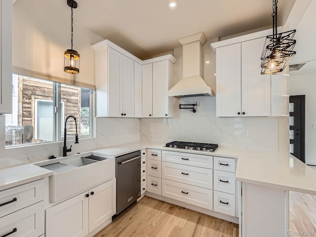 kitchen featuring stainless steel appliances, custom range hood, a sink, white cabinetry, and recessed lighting