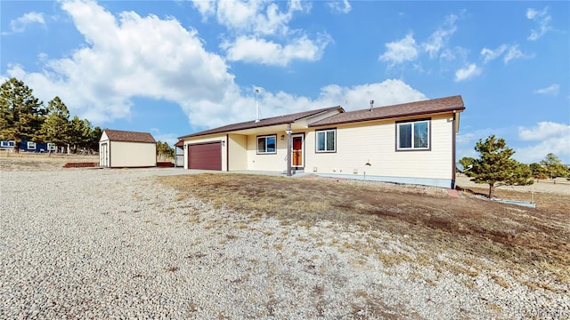 single story home with an outbuilding, driveway, an attached garage, and a storage unit