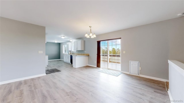 unfurnished living room featuring a chandelier, light wood-style flooring, and baseboards