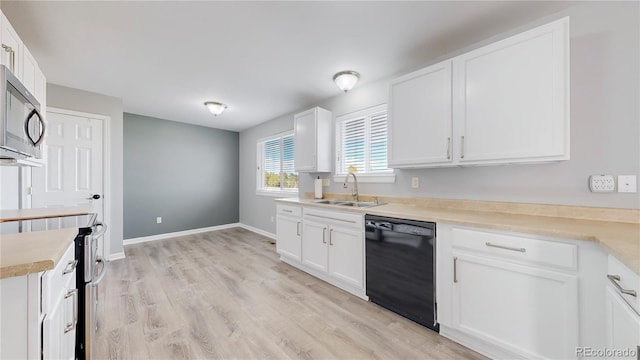 kitchen featuring appliances with stainless steel finishes, light wood-style floors, white cabinets, and a sink