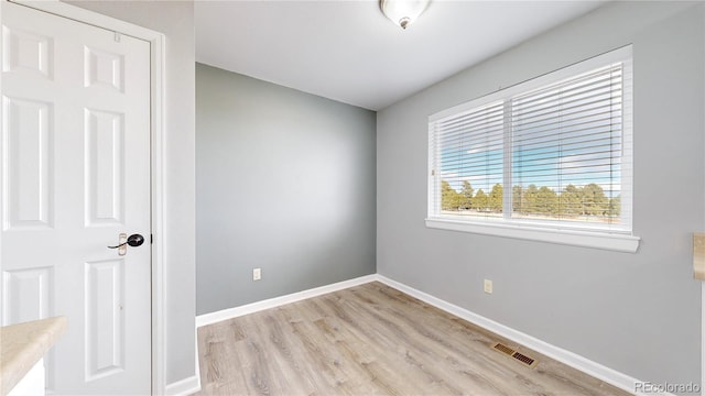 unfurnished room with light wood-style flooring, visible vents, and baseboards