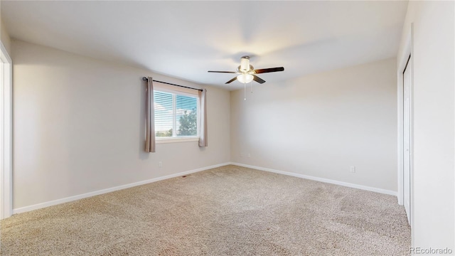 carpeted empty room with a ceiling fan and baseboards