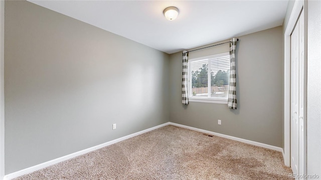 unfurnished room with carpet, visible vents, and baseboards