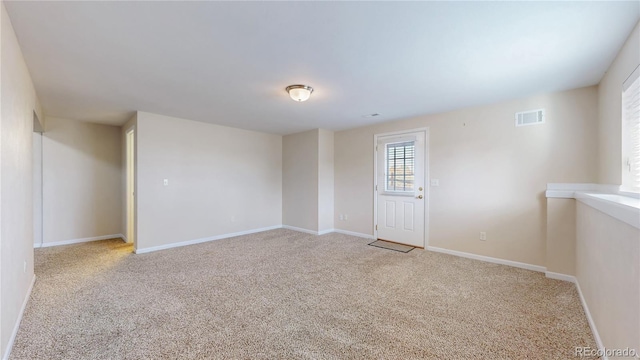 spare room with visible vents, light carpet, and baseboards