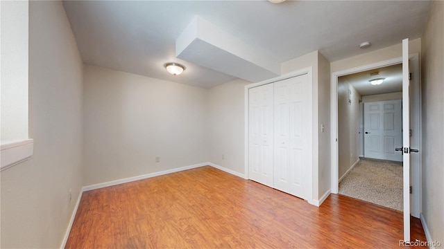 unfurnished bedroom featuring light wood finished floors, a closet, and baseboards