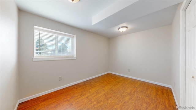 spare room with baseboards and wood finished floors