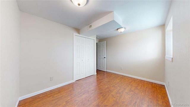 spare room featuring wood finished floors, visible vents, and baseboards