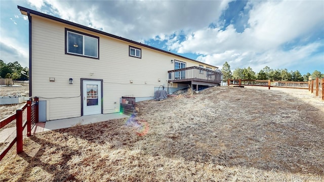 back of property with fence and a wooden deck