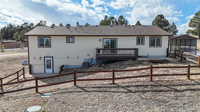 rear view of house with a carport, fence, and a wooden deck