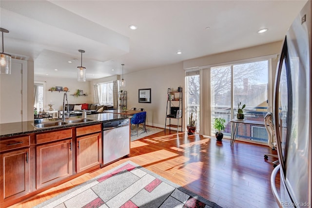 kitchen featuring appliances with stainless steel finishes, sink, pendant lighting, and light wood-type flooring