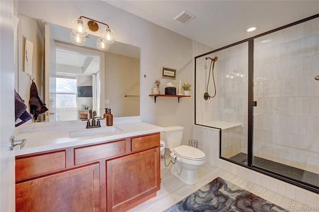 bathroom featuring vanity, a shower with shower door, and toilet