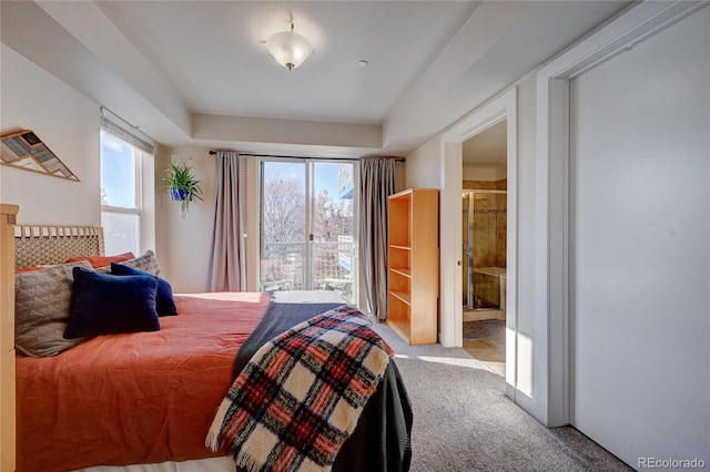 bedroom featuring multiple windows, carpet flooring, and ensuite bath