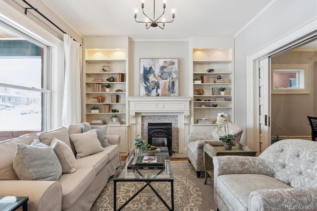 living area with built in features, ornamental molding, and an inviting chandelier