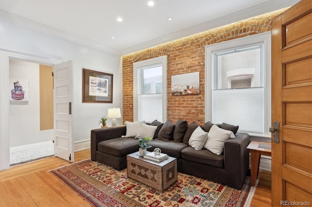 living room with light wood-type flooring, crown molding, and brick wall