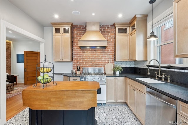 kitchen featuring sink, wall chimney range hood, dishwasher, high end white range, and hanging light fixtures