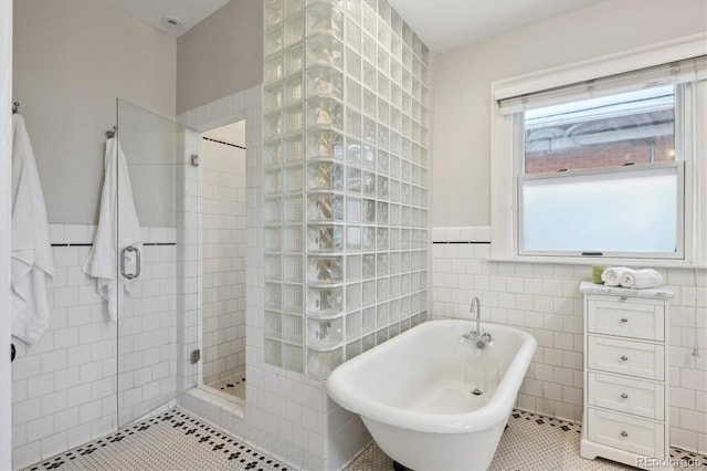 bathroom with tile patterned flooring, tile walls, and shower with separate bathtub