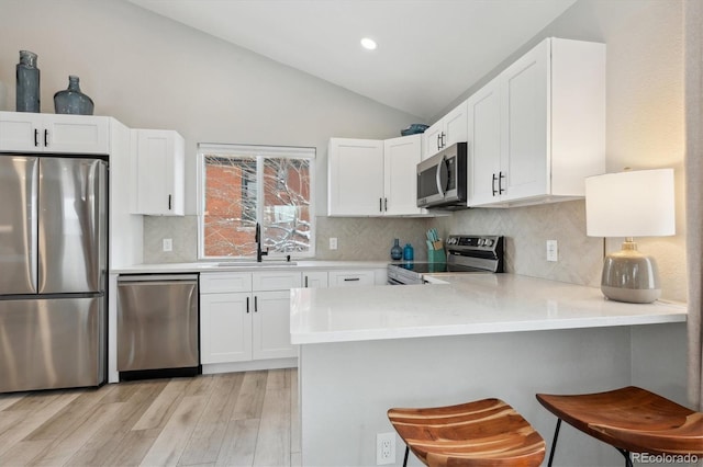 kitchen with kitchen peninsula, white cabinetry, a breakfast bar, and appliances with stainless steel finishes