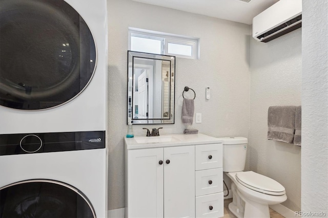 bathroom with a wall mounted AC, vanity, stacked washer / drying machine, and toilet