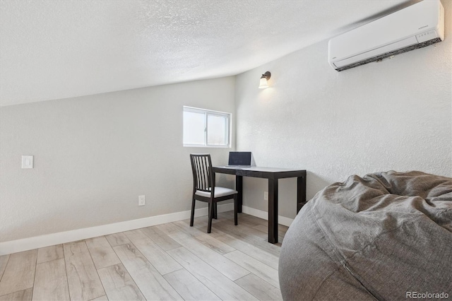 bedroom with a textured ceiling, light hardwood / wood-style flooring, vaulted ceiling, and a wall mounted AC