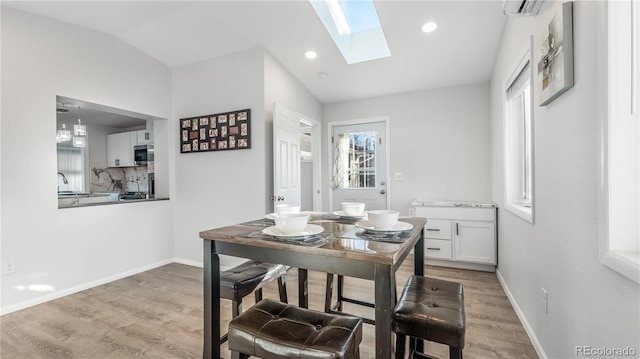 dining room with light wood finished floors, lofted ceiling with skylight, recessed lighting, and baseboards