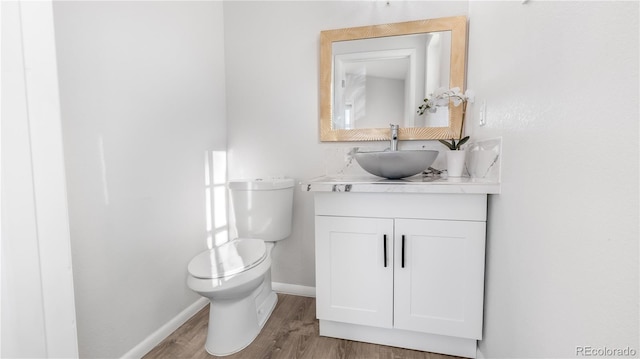 bathroom featuring baseboards, vanity, toilet, and wood finished floors