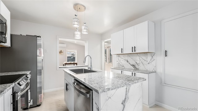 kitchen with a kitchen island with sink, a sink, hanging light fixtures, appliances with stainless steel finishes, and tasteful backsplash