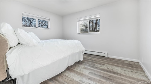 bedroom featuring baseboards, baseboard heating, and wood finished floors