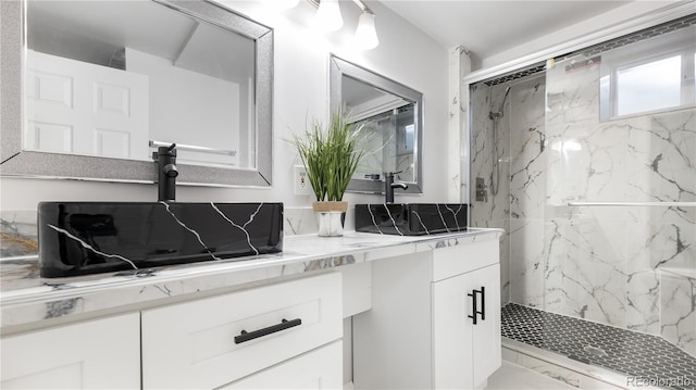 full bath featuring marble finish floor, a sink, a marble finish shower, and double vanity