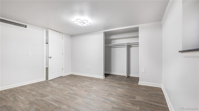 unfurnished bedroom with a closet, baseboards, and wood finished floors