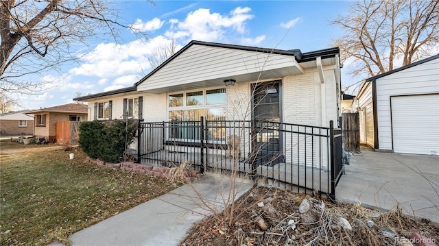 view of front of property with a porch, a garage, brick siding, an outdoor structure, and fence