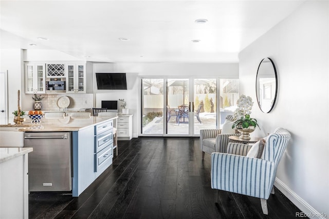 kitchen with white cabinetry, dishwasher, decorative backsplash, light stone counters, and dark wood-type flooring