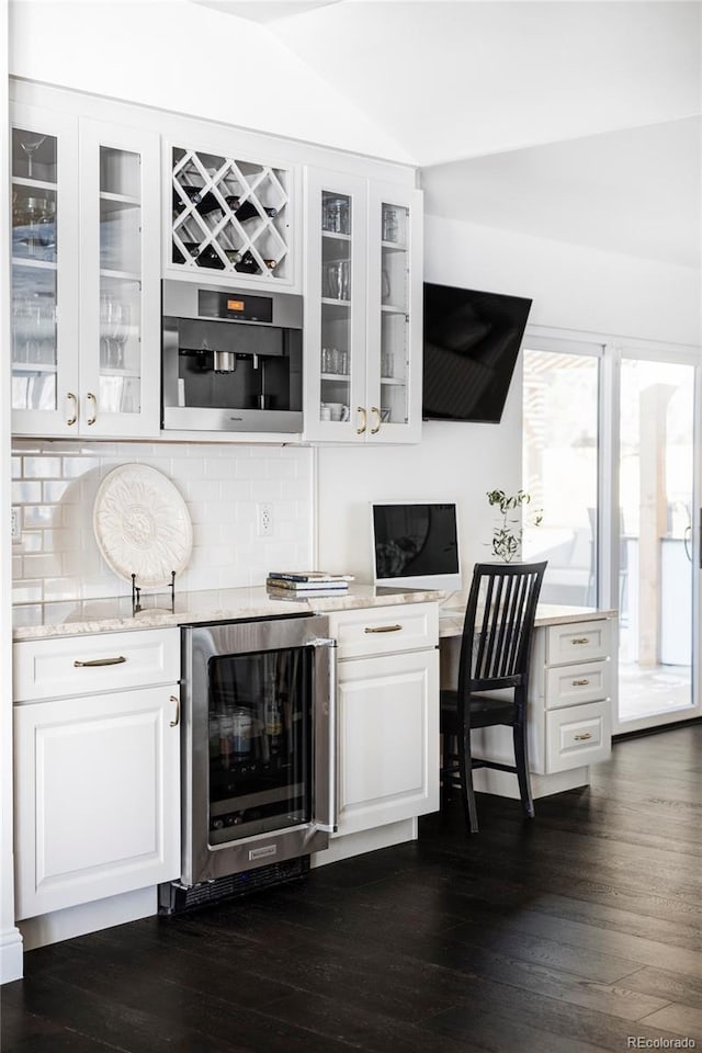 bar featuring lofted ceiling, dark hardwood / wood-style flooring, beverage cooler, decorative backsplash, and white cabinets