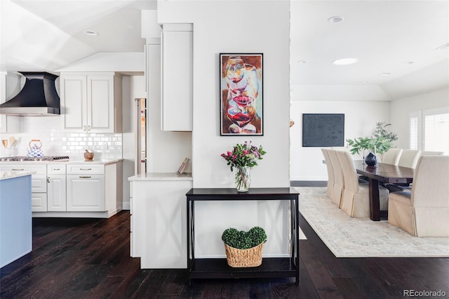 kitchen featuring lofted ceiling, white cabinets, dark hardwood / wood-style floors, and wall chimney exhaust hood