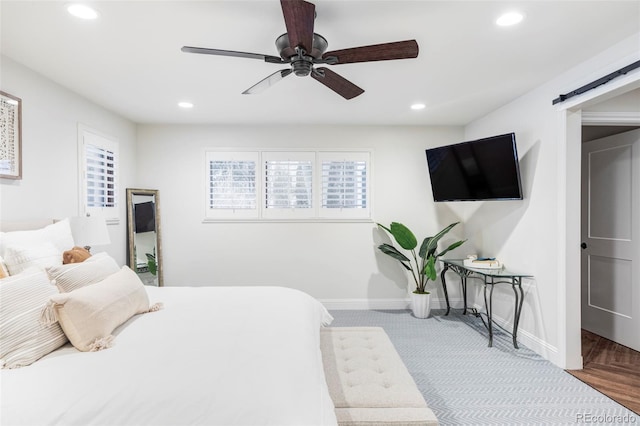 bedroom with ceiling fan and a barn door