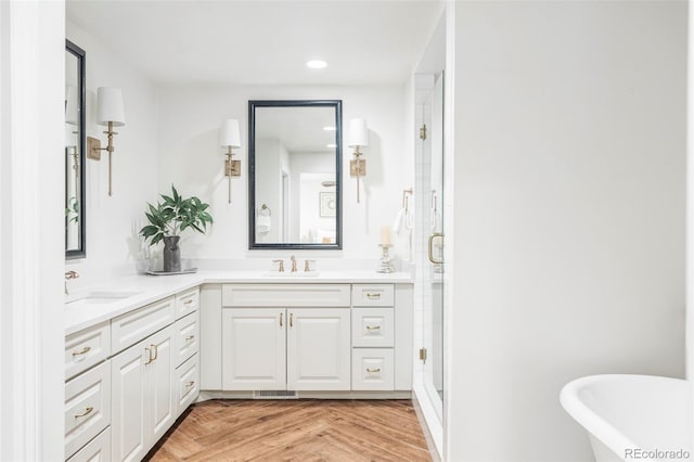 bathroom with parquet floors, vanity, and plus walk in shower