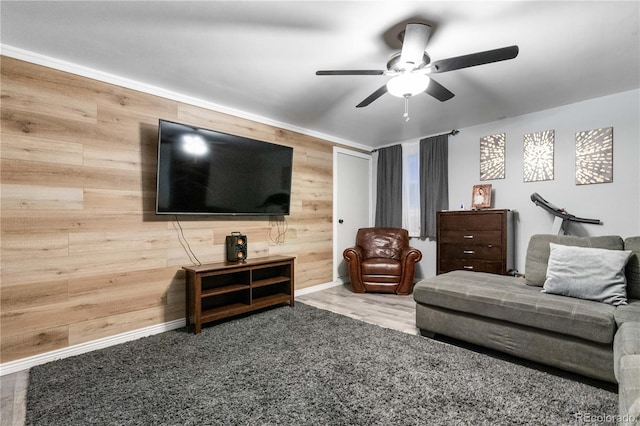 living room with ceiling fan, wood-type flooring, and wooden walls