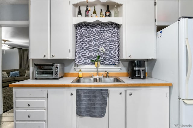 kitchen with white cabinetry, white fridge, sink, and ceiling fan