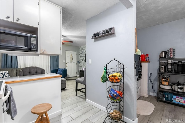 kitchen with white cabinetry, washer and dryer, ceiling fan, and a textured ceiling