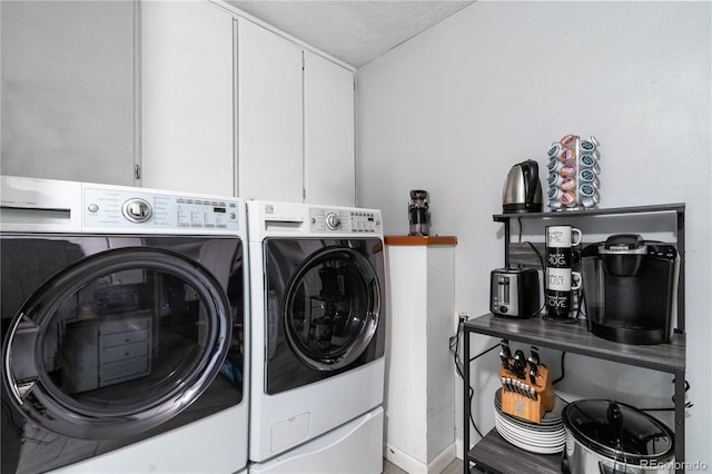 laundry area with cabinets, a textured ceiling, and washer and clothes dryer