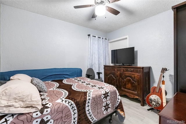 bedroom featuring ceiling fan, light hardwood / wood-style floors, and a textured ceiling