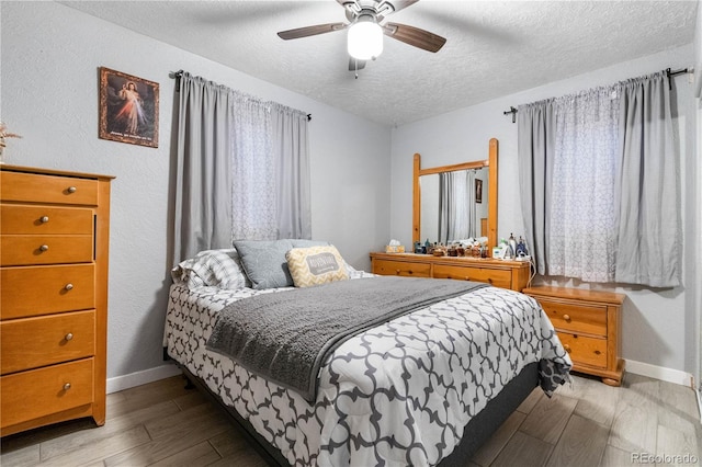 bedroom with ceiling fan, a textured ceiling, and light wood-type flooring