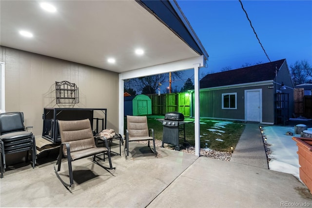 patio terrace at dusk featuring a storage shed and a grill