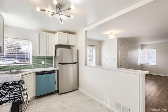 kitchen featuring sink, stainless steel appliances, backsplash, plenty of natural light, and white cabinets