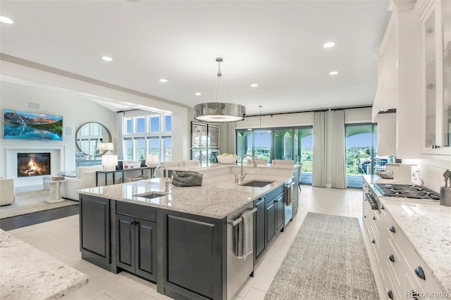 kitchen featuring white cabinets, a kitchen island with sink, sink, and a healthy amount of sunlight