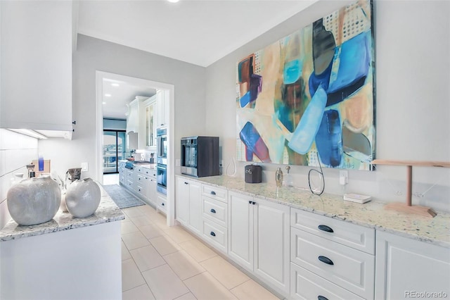 interior space with light stone countertops, stainless steel double oven, and white cabinetry