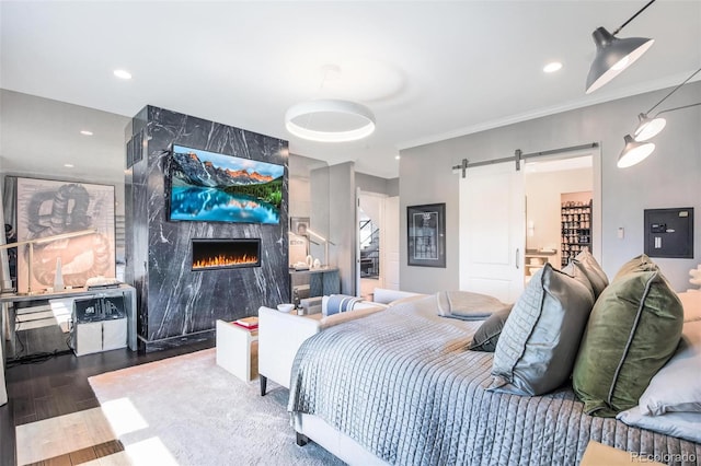 bedroom with a fireplace, a barn door, and wood-type flooring