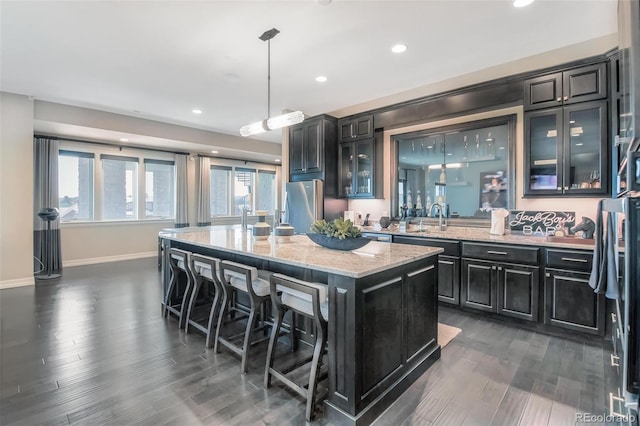 kitchen featuring stainless steel fridge, a kitchen island, a kitchen breakfast bar, decorative light fixtures, and dark hardwood / wood-style floors